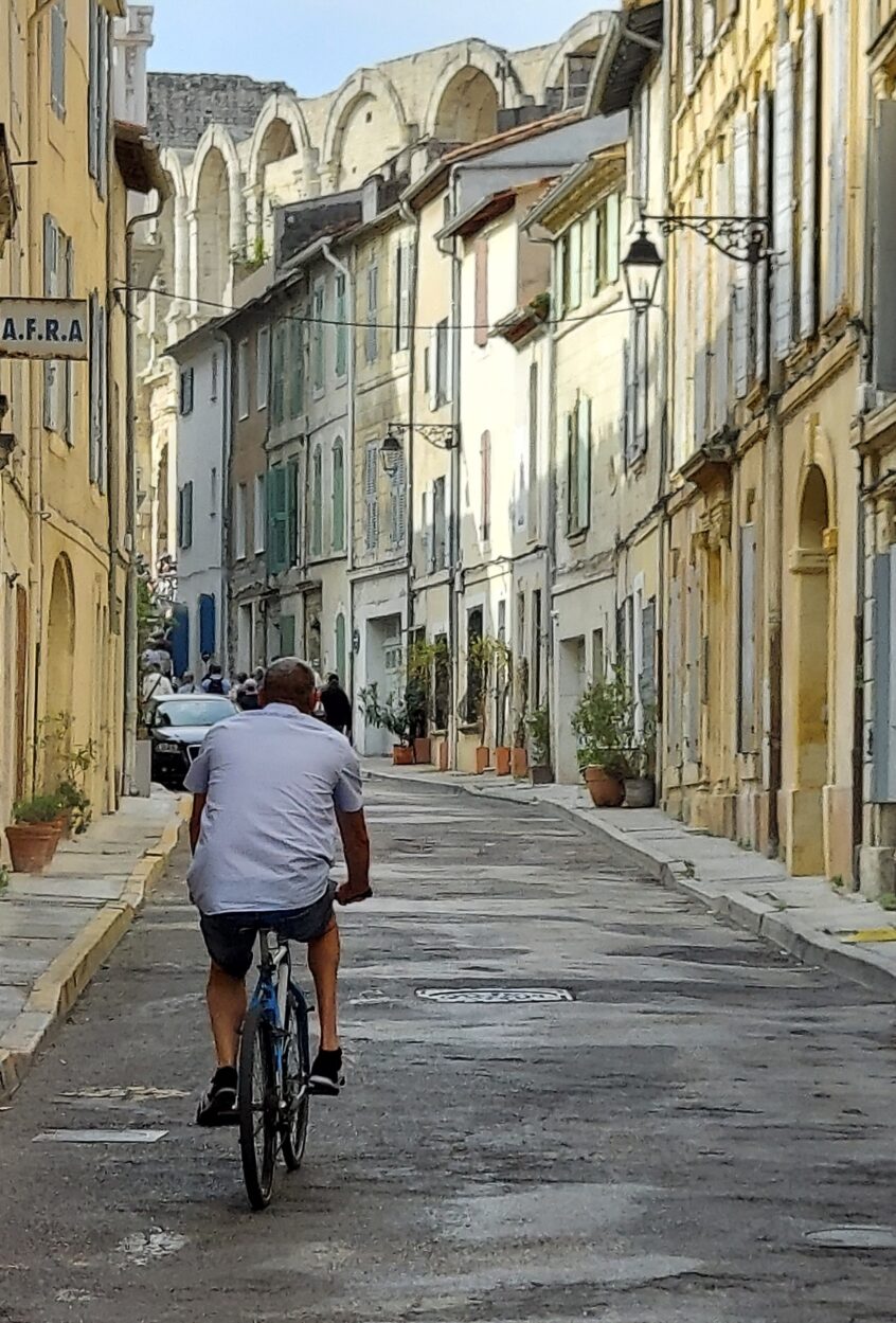 Man riding bicycle on hilly street in Arles